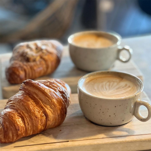 Två koppar cappucino och croissants